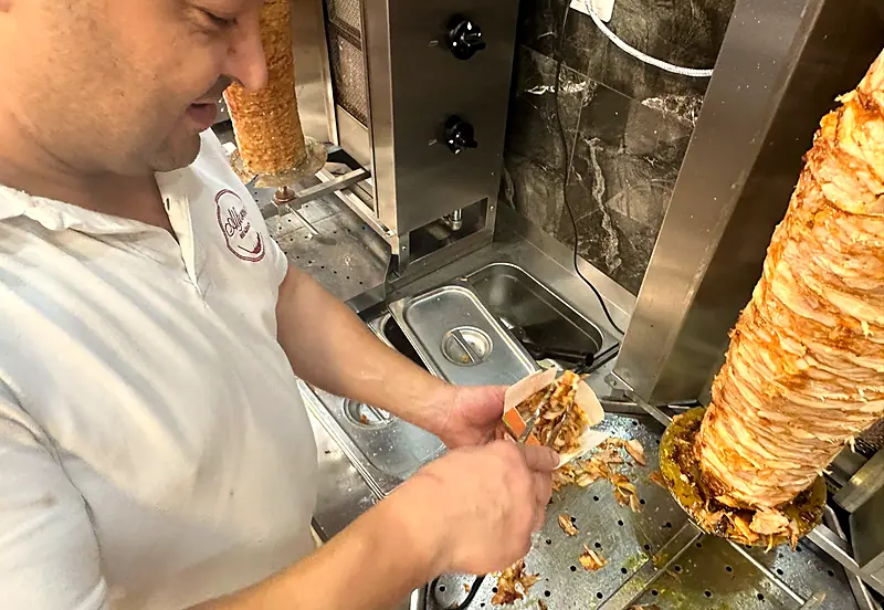 Hama s&nbsp;úsměvem krájí maso z&nbsp;grilu do kebab boxu
